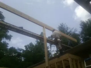 Carpenter setting a ridge beam over a new addition frame — Ice Dam Removal by Roofing Brothers in Duff