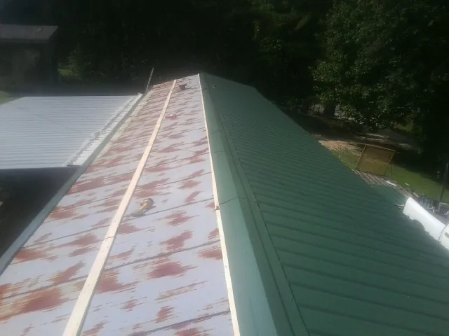 Old rusted panels beside newly installed green metal roofing — Wind Damage Roof Repair by Roofing Brothers in Duff