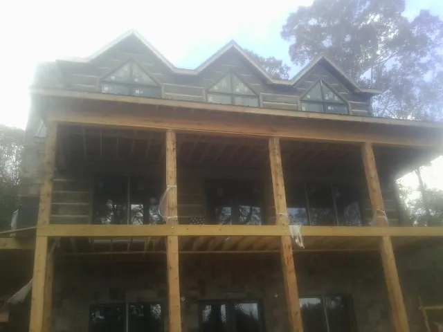 Dormers and porch framing on a large log home under construction — Roof Coating work by our crew in Duff