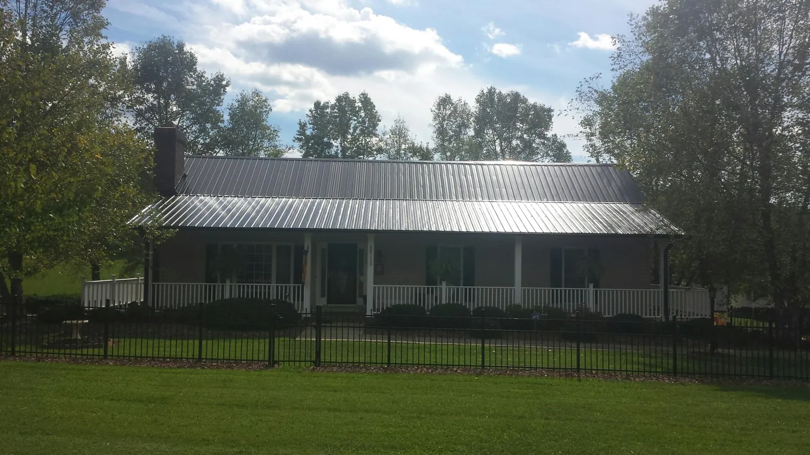Gray metal roof on a brick ranch with a full width front porch — Gutter Guard Installation work by our crew in Duff